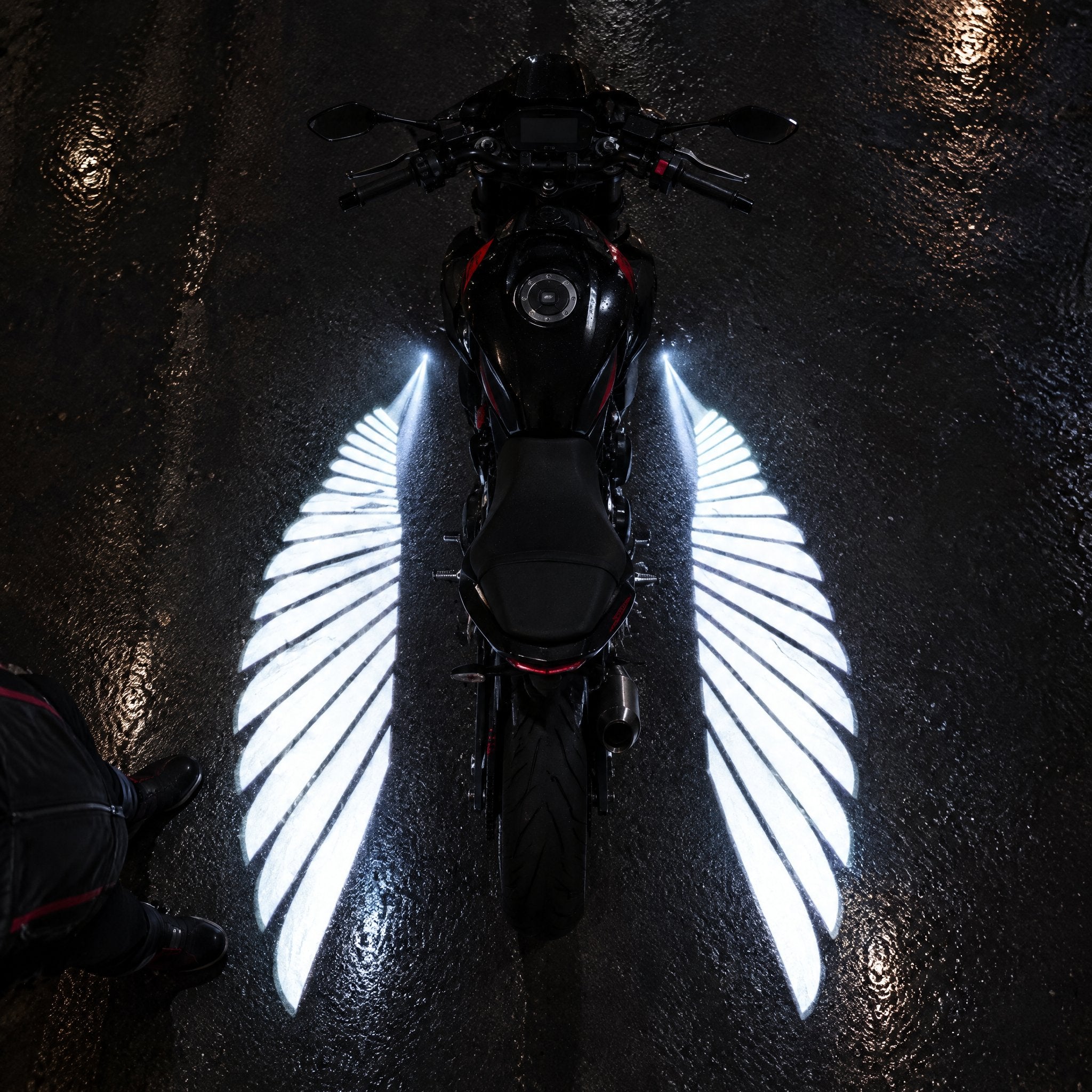 Top view of a motorcycle with white angel wing lights on wet asphalt